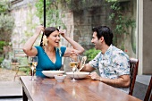 Playful couple eating together at table