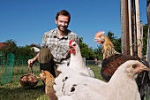 Bauer füttert Hühner im Freien