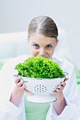 A young woman holding a colander of lettuce