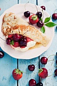 A crepe with vanilla cream, cherries and strawberries