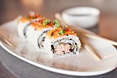 Spicy Tuna and Salmon Sushi Roll on a White Plate; Chopsticks