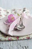 Cutlery with a bell flower and place card on a pink plate