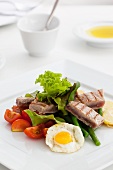 Quail's egg with tomato wedges, sliced potatoes and grilled tuna stripes