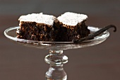 A vanilla pod and chocolate cake topped with icing sugar
