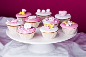 Cupcakes with pink and white glaze and sugar roses on a torte stand