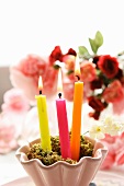 Lit candles in front of bouquet of roses