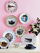 Holiday photos on patterned china plates on pink-painted wall