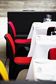 Colourful restaurant chairs in front of laid tables