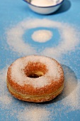 A doughnut sprinkled with sugar on a blue surface