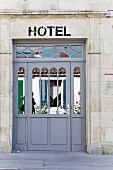 Verspiegelte Eingangstür eines Hotels mit historischer Steinfassade