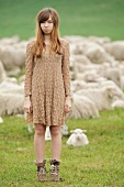 Young girl standing in a pasture in front of sheep