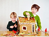 Two boys decorating a gingerbread house