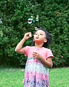 Dark haired girl blowing soap bubbles