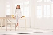 Little girl in pajamas laughing while sitting on a breakfast table