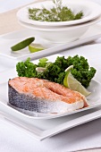 Raw salmon steak with green cabbage and a lemon wedge