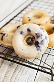 Blueberry doughnuts with icing sugar on a wire rack