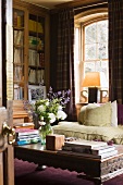 View through open door of coffee table with carved wooden border and sofa in corner of traditional living room