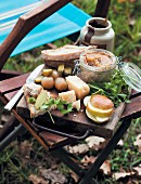 Picknick im Herbst mit Brotaufstrich, Käse & Obst auf Stuhl im Freien