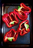 Halved red peppers on a baking tray (seen from above)