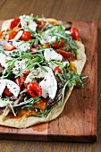 Unleavened bread topped with tomatoes, rocket and mozzarella