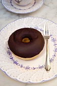 A chocolate-glazed doughnut and a fork on a plate