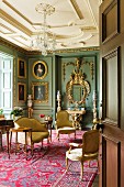 Barockes Besprechungszimmer mit Polstermöbeln, goldgerahmten Ölportraits und rotem Teppich