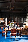 Festively set dining table in wood-panelled great hall with blue rug