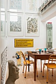 Holztisch mit gelben Metallstühlen, Schild mit Bazon Brock Zitat und Werke von Eduardo Paolozzi in der Küche
