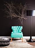 50's style turquoise armchair between modern floor lamps and upholstered ottoman in front of a black wall