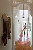 View through white, carved wooden archway of woman and dog in narrow hallway of renovated period building