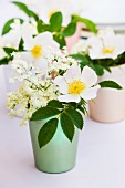 Wild roses and elder flowers in colorful metal containers