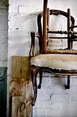 Antique, dilapidated chairs hanging on whitewashed brick wall