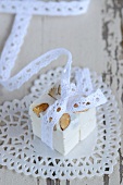 A cube of nougat decorated with a lace ribbon