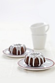 Mini Chocolate Cakes with Icing on Plates; Cups
