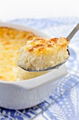 Spoonful of Baked Cheese Grits; Baking Dish in Background