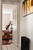 View from hallway with old radiator through open door to bedroom with handmade quilt