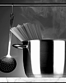 Spaghetti in a stainless steel pot and a hanging ladle