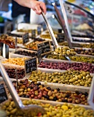 Various types of preserved olives on a market stand