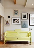 Yellow, vintage wooden bench against wall with gallery of contemporary art