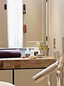 Verschiedene Badutensilien auf rustikalem Waschtisch aus Holz vor halb geöffnetem Fensterladen