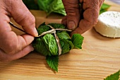 Goat's cheese being wrapped in masterwort leaves