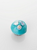 A turqoise cupcake decorated with baby motifs