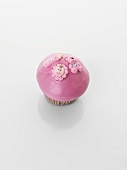 A pink cupcake decorated with baby motifs