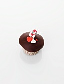 A cupcake decorated with a teddy bear and hearts