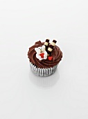 A cupcake decorated with chocolate cream, a teddy bear and hearts