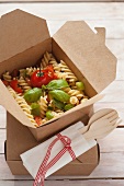 Fusilli with tomatoes, courgette and basil in a takeaway box