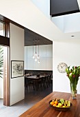 Fruit bowl on wooden table and view into modern dining room through floor-to-ceiling doorway