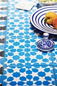 Blue and white crockery on blue and white tiled table top with floral pattern