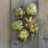 Five artichokes on a wooden surface