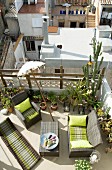 Airy roof terrace with comfortable wicker furniture, many potted plants, Indian parasol and view onto neighbouring terraces